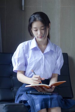 Asya Taylandlı lise öğrencisi üniforması. Güzel kız bir kitap okumuş.