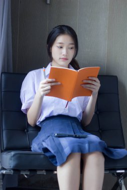Asya Taylandlı lise öğrencisi üniforması. Güzel kız bir kitap okumuş.
