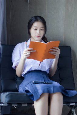 Asya Taylandlı lise öğrencisi üniforması. Güzel kız bir kitap okumuş.