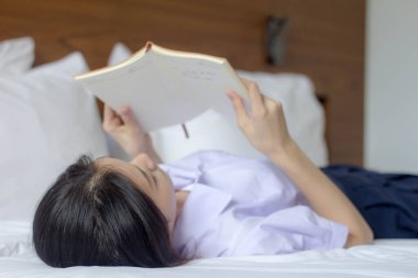 Asya Taylandlı lise öğrencisi üniforması. Güzel kız bir kitap okumuş.