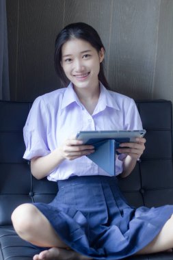 Asia Thai lise öğrencisi üniforması güzel kız tabletini kullanıyor.