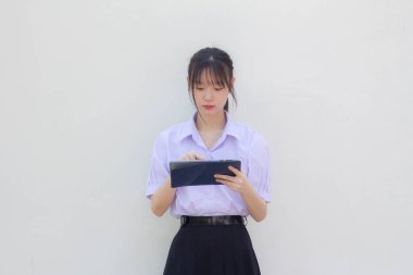 Asia Thai lise öğrencisi üniforması güzel kız tabletini kullanıyor.