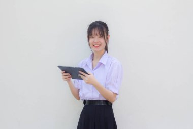 Asia Thai lise öğrencisi üniforması güzel kız tabletini kullanıyor.