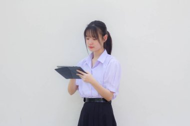 Asia Thai lise öğrencisi üniforması güzel kız tabletini kullanıyor.