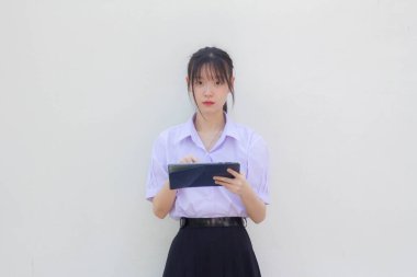 Asia Thai lise öğrencisi üniforması güzel kız tabletini kullanıyor.