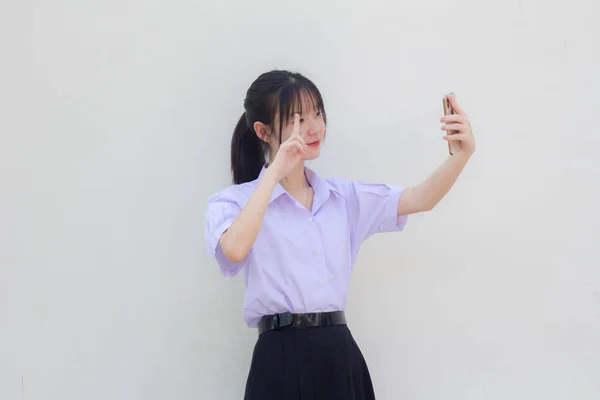 アジアタイ高校生制服美少女使用彼女のスマートフォンSelfie — ストック写真