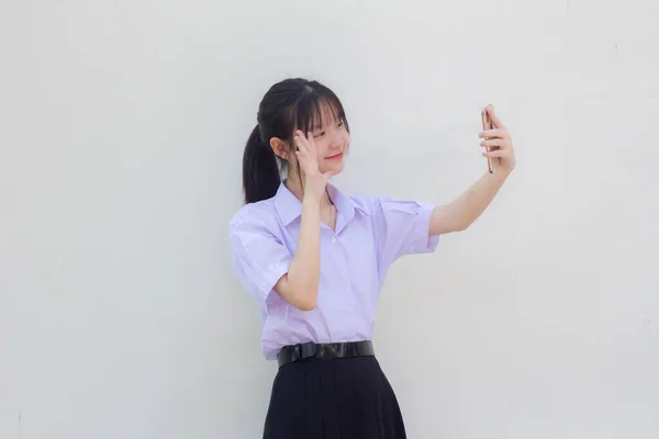 アジアタイ高校生制服美少女使用彼女のスマートフォンSelfie — ストック写真