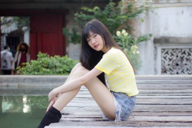 Portrait of thai china adult beautiful girl yellow shirt blue jeans relax time