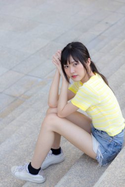 Portrait of thai china adult beautiful girl yellow shirt blue jeans relax time