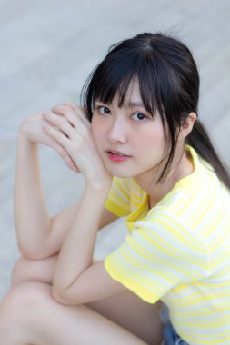 Portrait of thai china adult beautiful girl yellow shirt blue jeans relax time