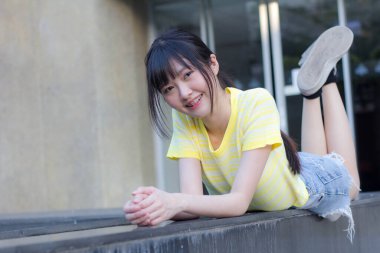 Portrait of thai china adult beautiful girl yellow shirt blue jeans relax time