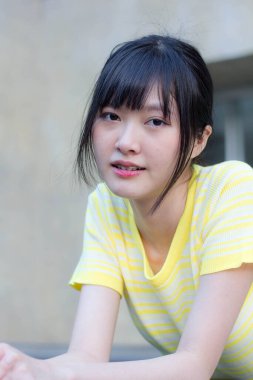 Portrait of thai china adult beautiful girl yellow shirt blue jeans relax time