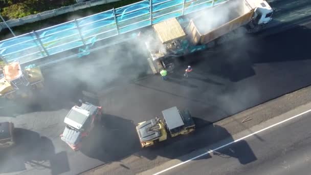 Vue aérienne des travaux routiers, asphalte pavé pose une nouvelle couche d'asphalte, Rouleaux routiers conduire sur une nouvelle route. Réparation de la chaussée. Bâtiment s Nouvelle route avec la réparation de la route. Machines lourdes. — Video