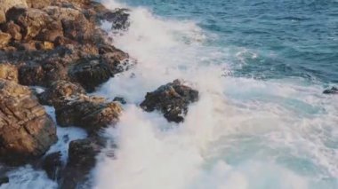 Deniz dalgaları kayalık kıyıya vurur ve su ve köpük oluşturur..