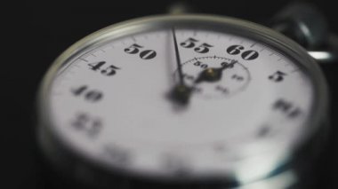Klasik bir metalik, mekanik analog kronog kronometrenin karanlık arka planda saniyeleri sayarken makro çekimi. Zaman yönetimi kavramı. 
