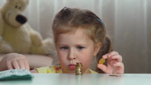 小さなブロンド女の子ともに集中見てカウントコインのためにお金のために未来. — ストック動画