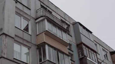 Gri gökyüzüne karşı iç karartıcı bir apartman. Sovyet sonrası bir şehirde gettoda yaşam. Kirli balkonlar ve yüksek katlı bir binanın ön cephesi..
