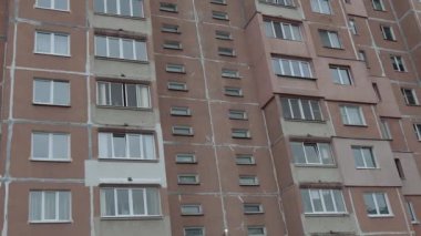 Gri gökyüzüne karşı iç karartıcı bir apartman. Sovyet sonrası bir şehirde gettoda yaşam. Kirli balkonlar ve yüksek katlı bir binanın ön cephesi..