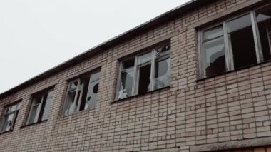 İki katlı tuğla bir binanın camları kırılmış. Savaş bölgesinde gri gökyüzüne karşı tahrip edilmiş terk edilmiş bir bina..
