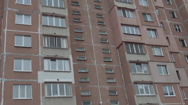 Depressief flatgebouw tegen een grijze lucht. Leven in een getto in een voormalige Sovjetstad. Vuile balkons en de gevel van een paneel hoogbouw. — Stockvideo