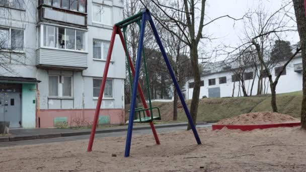 A lone swing swings in the wind at an unknown playground in a depressing backyard of an Eastern European ghetto. Concept of kidnapping, bullying. — Stock Video