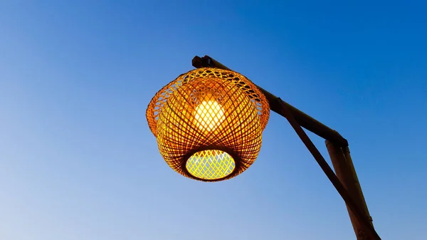 Arka planda mavi gökyüzü ile asılı duran bambu lamba.