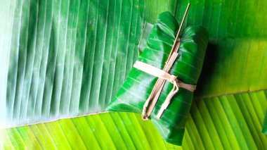 Muz yaprakları üzerinde yapışkan pilavlı muz demeti.