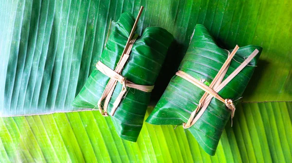 Muz yaprakları üzerinde yapışkan pilavlı muz demeti.