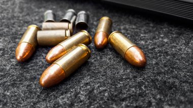 Siyah yapay tabanca ve koyu gri kumaş üzerinde mermiler. Sosyal, kişisel ve atış sporu ekipmanlarının güvenliği kavramı