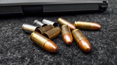 Siyah yapay tabanca ve koyu gri kumaş üzerinde mermiler. Sosyal, kişisel ve atış sporu ekipmanlarının güvenliği kavramı