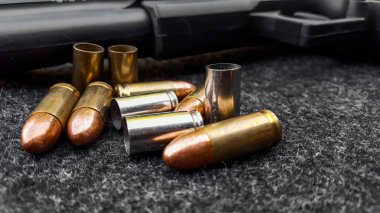 Siyah yapay tabanca ve koyu gri kumaş üzerinde mermiler. Sosyal, kişisel ve atış sporu ekipmanlarının güvenliği kavramı