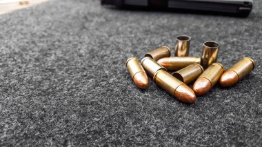 Siyah yapay tabanca ve koyu gri kumaş üzerinde mermiler. Sosyal, kişisel ve atış sporu ekipmanlarının güvenliği kavramı