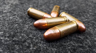 Koyu gri kumaş üzerine altın renkli parlak mermiler sosyal, kişisel ve atış sporu malzemelerinin güvenliği için konsept..