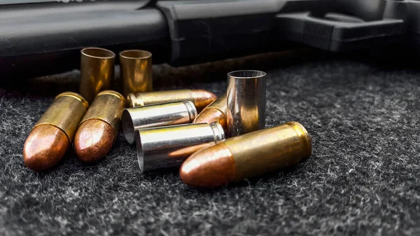 Siyah yapay tabanca ve koyu gri kumaş üzerinde mermiler. Sosyal, kişisel ve atış sporu ekipmanlarının güvenliği kavramı