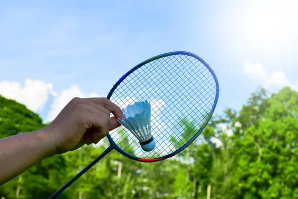 Shuttlecock holding by hand in front of the racket and ready to be served