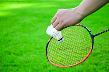 Shuttlecock holding by hand in front of the racket and ready to be served