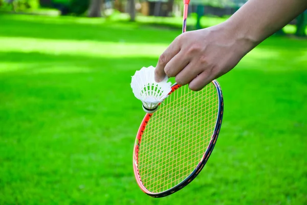 Shuttlecock holding by hand in front of the racket and ready to be served