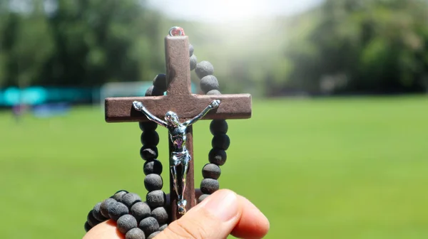 Brown rosary wooden cross holding in hand soft and selective focus on the cross
