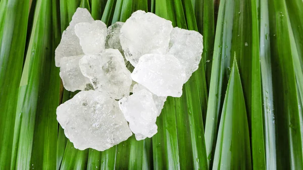 Crystal clear alum cubes or Potassium alum on green leaf. Chemical compound substance. Concept for beauty , spa and underarm treatment industrial.