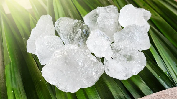 Crystal clear alum cubes or Potassium alum on green leaf. Chemical compound substance. Concept for beauty , spa and underarm treatment industrial.