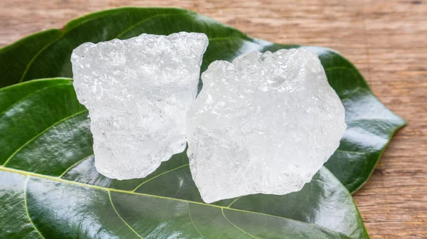 Crystal clear alum cubes or Potassium alum on green leaf. Chemical compound substance. Concept for beauty, spa and underarm treatment industrial.