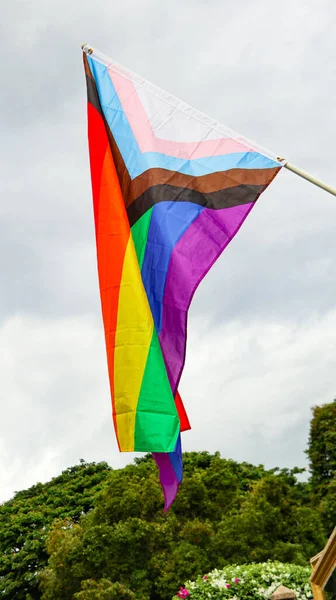LGBT gökkuşağı bayrağı dalgalanıyor ve dünya çapında LGBTQ + topluluğunu geliştirmek için arka planda mavi gökyüzü var.