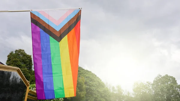 LGBT gökkuşağı bayrağı dalgalanıyor ve dünya çapında LGBTQ + topluluğunu geliştirmek için arka planda mavi gökyüzü var.