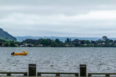 Yüzen uçaklar ve eğlence aracı göl boyunca dalgalara ve havaya çarpmayı bekliyor. Mavi Göl, Rotarua, Yeni Zelanda