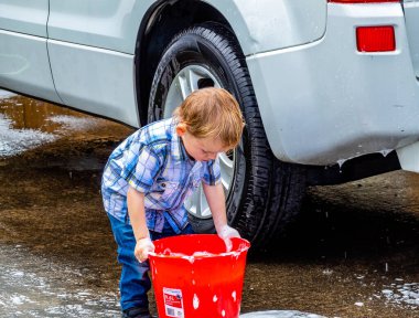 Çocuklar arabayı yıkamaya, suda oynamaya ve köpüklenmeye yardım ediyor. Taranaki, Yeni Zelanda