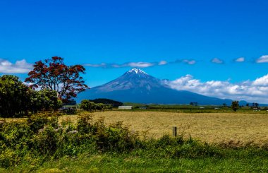 Taranaki Dağı kırsal alanda araba sürerken gökyüzüne doğru yükselir. Taranaki, Yeni Zelanda