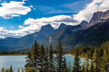 Three sisters overlook shimmering Quarry Lake. Canmore Nordic PP. Alberta, Canada