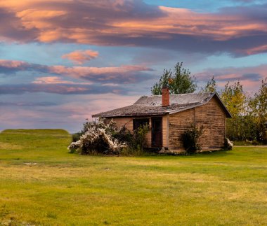 Kırsal çiftlik binalarının üzerinde güneş batıyor. Midland İl Parkı, Alberta, Kanada