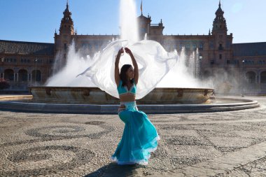 Meydanda dans eden genç ve güzel bir dansçı. O, elinde beyaz bir peçeyle açık mavi giyinmiş. Afrika ve Asya 'dan gelen dünya folklor kavramı.