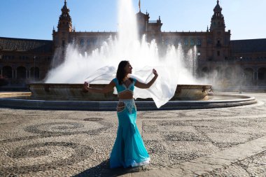 Meydanda dans eden genç ve güzel bir dansçı. O, elinde beyaz bir peçeyle açık mavi giyinmiş. Afrika ve Asya 'dan gelen dünya folklor kavramı.